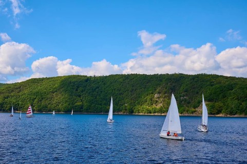 Sailboats sailing on the wide lake in front of a wooded hilly landscape, summer, Rursee,
