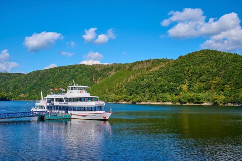 Passenger ship anchored at the jetty, in front of green hills under a blue sky, summer, Rursee,