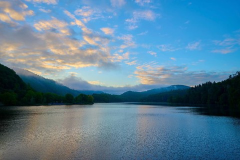 Gentle morning colour reflected on the quiet lake, surrounded by hills and clouds, summer, Rursee,