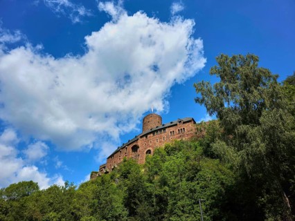 A medieval castle on a wooded hill under a blue sky with clouds, summer, Heimenbach, Simmerath,