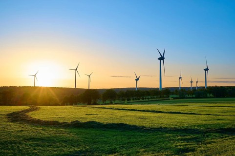 Wide landscape with wind turbines and trees while the sun colours the sky, summer, Rohren,