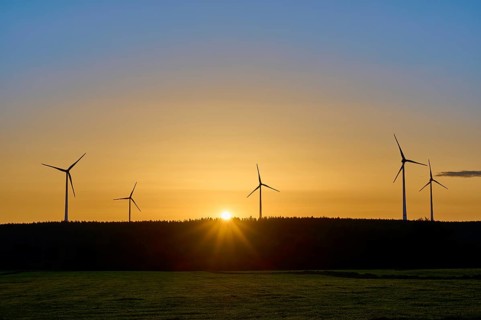 Sunrise, behind a row of wind turbines, bathing the landscape in warm light, summer, Rohren,