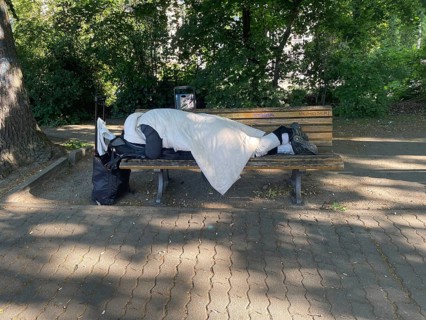 Homeless man sleeping on a park bench in Viktoriapark, District Friedrichshain-Kreuzberg, Social