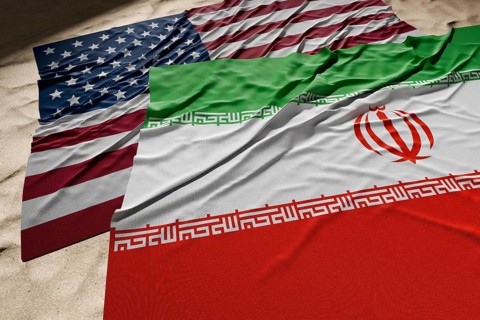 American and Iranian flags resting on desert sand