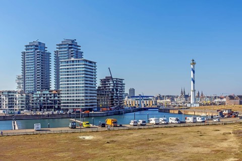 Motorhomes parked in front of lighthouse Lange Nelle and skyline of the Oosteroever quarter in