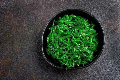 Chuka salad, made from fresh seaweed, with sesame dressing, served in a black bowl, with chopsticks