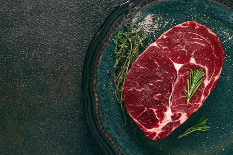 Steak made from fresh beef, with herbs and various spices, on a plate, ready to cook, there are no