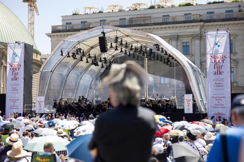 A visitor protects himself from the sun with a newspaper on his head at the Staatsoper fÃ¼r alle, a