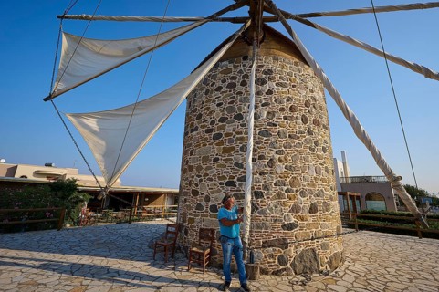 Stone mill with sails, a man pulling a rope under a blue sky, windmill, Antimacheia, Kos,