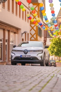 Car in a cobblestone alley decorated with colourful lanterns under bright daylight, Deer E, car