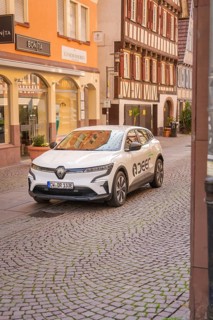An electric car in front of half-timbered houses in a historic shopping street, Deer E, car