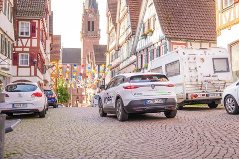 Cars parked in an old town, decorated with colourful garlands and a church in the background, Deer