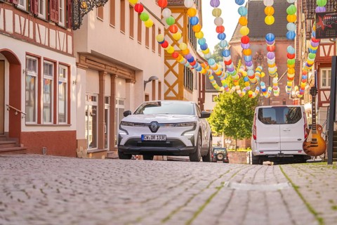 White car in an alley decorated with colourful lanterns under a blue sky, Deer E, car sharing,