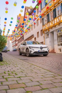 A car drives under colourful garlands in a cobbled street, Deer E, car sharing, electric car, Calw,