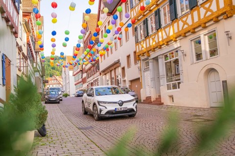 A car drives through a street decorated with colourful garlands in an old town, Deer E, car