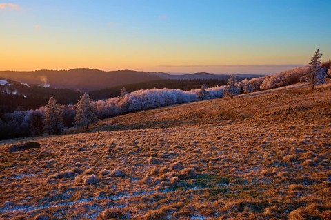 Frosty hills under a bright orange evening sky, winter, Route de Cretes, Hohneck, La Bresse,