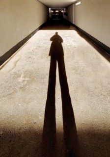 Long shadow of a person in the tunnel of the underpass to the railway tracks, train station, Bad