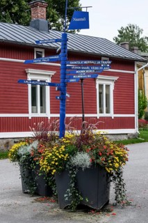 Street scene in the old town of Naantali, colorful signposts and flowers in front of a red wooden