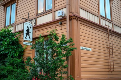 Street scene in the old town of Naantali, orange-painted wooden house with road signs and lush