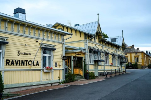 Yellow restaurant building with decorative wooden design, located on a quiet street, conveys
