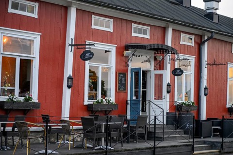 Red wooden café building with outdoor seating area, inviting and traditionally designed, Naanatali,