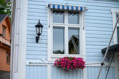 Street scene in the old town of Naantali, light blue wooden house with white windows and blooming