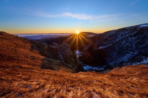 Golden sunbeams over mountain landscape under clear blue sky, looking towards the Rhine Valley,