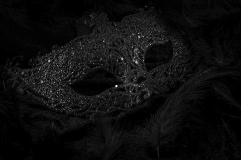Black mask on dark background, contrasting carnival atmosphere