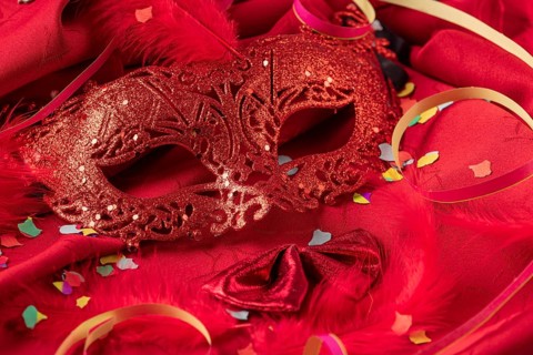 Red mask with confetti, feathers and colorful streamers, carnival