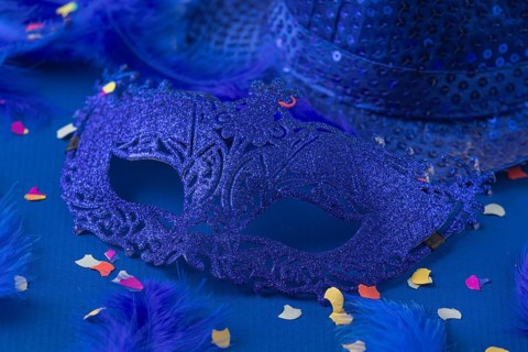 Blue mask with feathers, confetti and hat on blue background, carnival