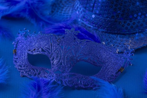 Blue mask with matching feathers and hat on blue background, carnival