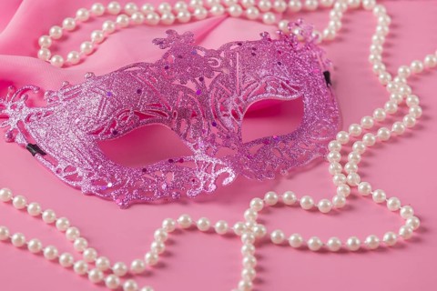 Glittering pink mask with pearl jewelry on a pink fabric