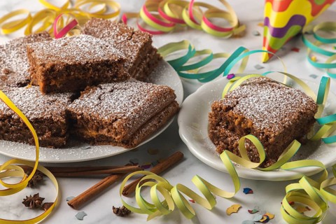 Spice cake with powdered sugar surrounded by colorful streamers and confetti