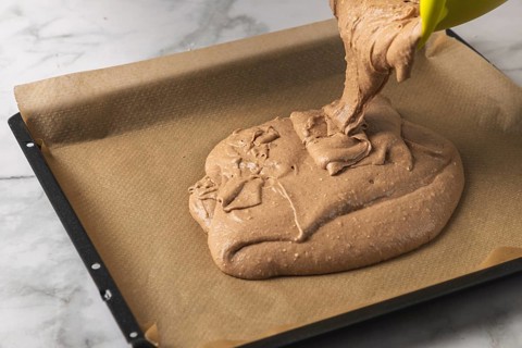 Cocoa dough is poured onto a baking sheet lined with baking paper