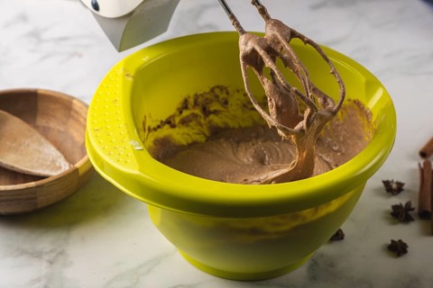 Electric mixer processes cocoa dough in a yellow bowl