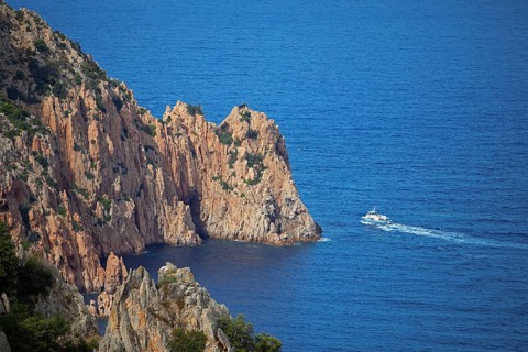 Visitors on an excursion boat look at bizarre rock formations at Capo Rosso, Piana, Corse-du-Sud