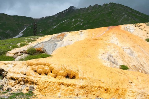 Yellow rocky landscape with green mountains and dark cloudy sky, Bidara Travertine, Travertine,