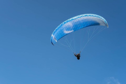 Single paraglider in the blue sky symbolizing freedom and adventure, paraglider near Gudauri,