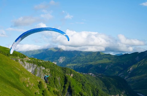 Paraglider flying with blue sky and mountain scenery, a sense of freedom and adventure, paraglider,