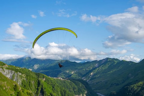 A paraglider in a vast mountain landscape with blue sky and white clouds, paraglider, paraglider