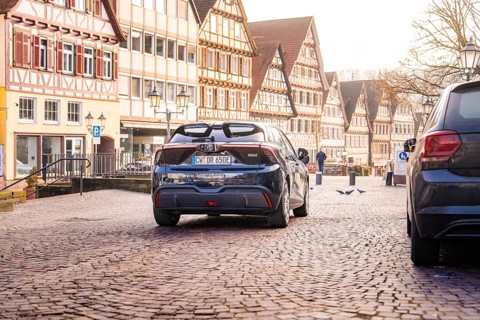 Car drives through a historic street surrounded by traditional half-timbered houses and