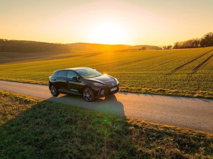 Black car on a dirt road at sunset, wide landscape in the background, MG4 electric car, deer e-car