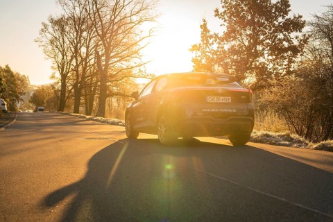 Vehicle driving on a road in atmospheric evening sunlight and casting shadows, MG4 electric car,