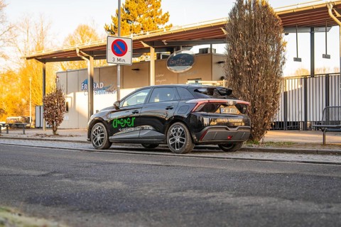 Car parked near an outdoor pool building with evening lights and signs, MG4 electric car, Deer