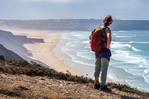 Woman with backpack, above beach Prai de Bordeira north of village Carrapateira, coast of western
