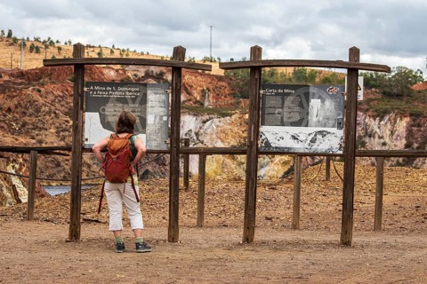 Woman reading explanatory panel, entrance to Mina de Sao Domingos, historic copper open-pit mine,