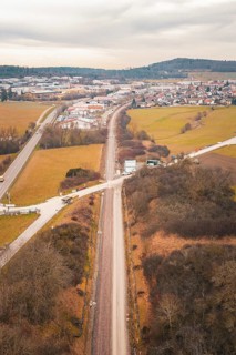 Aerial view of a railway line through snowy fields near a village, using a tamping machine at the