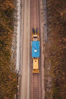 Aerial view of a yellow train during construction in a winter environment, tamping machine used on