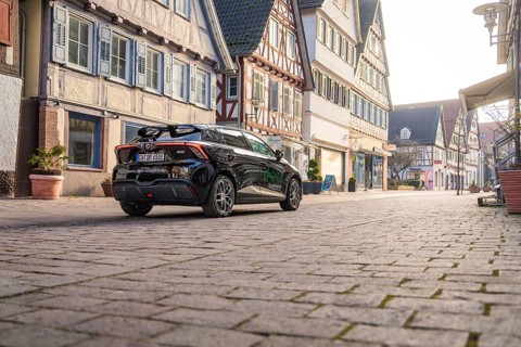 Car drives quietly through a street with traditional architecture and half-timbered houses, MG4