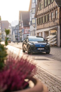 Black car parked on a paved street in a historic town with half-timbered houses in daylight, MG4